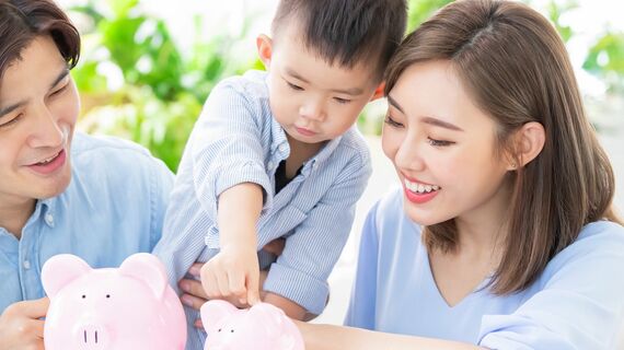 貯金箱にお金を入れる親子